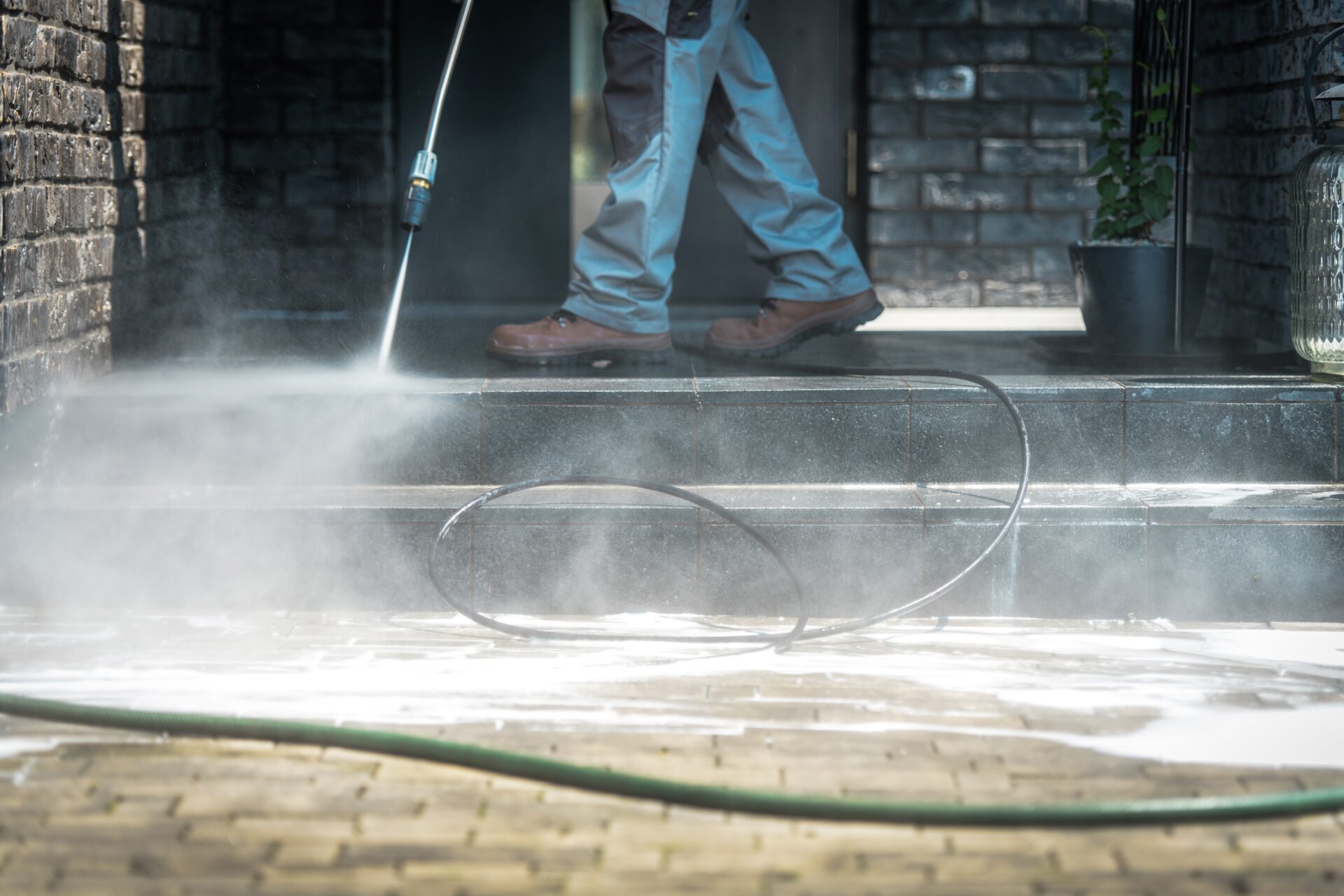 Pressure Washer Cleaning Time. Men Cleaning Outside House Stairs with Power High Pressured Cleaner. Ceramic Stairs and Home Entrance. Closeup Photo.